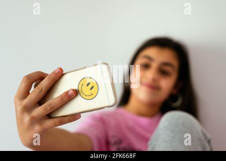 Female teenager using smartphone on bed and taking photos Stock Photo