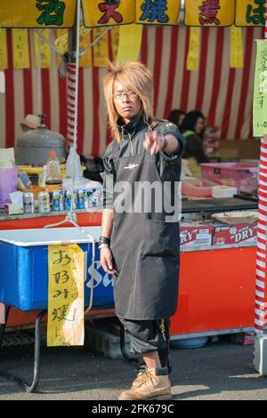 Japanese male gyaruo with deep suntan working on food stall at Yasukini Shrine, Tokyo, Japan Stock Photo