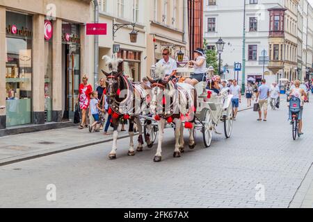 KRAKOW, POLAND - SEPTEMBER 3, 2016: Horse carriage with tourists is passing through streets of Krakow. Stock Photo