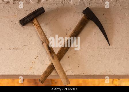 Hammer and ice pick on the wall of the house. Old tools left behind by the workers in the mines. Stock Photo