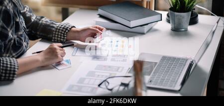 Closeup of female ux developer and ui designer about mobile phone app interface in living room at home.Creative digital development agency concept Stock Photo