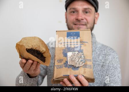 Nuremberg, Germany. 19th Apr, 2021. Ralph Haydl holds a coffee filter with old coffee grounds in one hand and a mushroom growing kit with pigeon blue oyster mushrooms in the other - a mushroom substrate consisting of coffee grounds with mushroom spawn. The 41-year-old from Nuremberg has been selling mushroom cultivation sets for several years, with which one can grow various oyster mushrooms, yellow lemon mushrooms or pink rose mushrooms at home. (to dpa "Delicious mushrooms on old coffee - niche or trend?") Credit: Daniel Karmann/dpa/Ģ����ý Live News Stock Photo