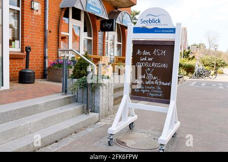 Norddorf, Germany. 28th Apr, 2021. A sign for the start of the project 'Model Region Kreis Nordfriesland' stands in front of the Hotel Seeblick on Amrum. As of May 1, overnight guests may once again be received on the North Frisian islands under certain conditions. Credit: Frank Molter/dpa/Alamy Live News Stock Photo