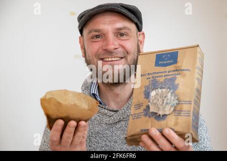Nuremberg, Germany. 19th Apr, 2021. Ralph Haydl holds a coffee filter with old coffee grounds in one hand and a mushroom growing kit with pigeon blue oyster mushrooms in the other - a mushroom substrate consisting of coffee grounds with mushroom spawn. The 41-year-old from Nuremberg has been selling mushroom cultivation sets for several years, with which one can grow various oyster mushrooms, yellow lemon mushrooms or pink rose mushrooms at home. (to dpa "Delicious mushrooms on old coffee - niche or trend?") Credit: Daniel Karmann/dpa/Ģ����ý Live News Stock Photo