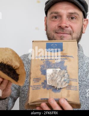 Nuremberg, Germany. 19th Apr, 2021. Ralph Haydl holds a coffee filter with old coffee grounds in one hand and a mushroom growing kit with pigeon blue oyster mushrooms in the other - a mushroom substrate consisting of coffee grounds with mushroom spawn. The 41-year-old from Nuremberg has been selling mushroom cultivation sets for several years, with which one can grow various oyster mushrooms, yellow lemon mushrooms or pink rose mushrooms at home. (to dpa "Delicious mushrooms on old coffee - niche or trend?") Credit: Daniel Karmann/dpa/Ģ����ý Live News Stock Photo