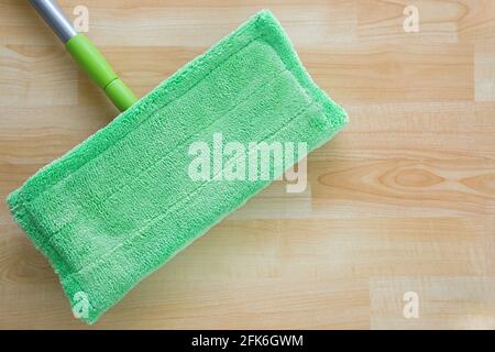 New clean green microfiber mop floor wiper cleaning sweeping tool with silver handle on wooden floor with copyspace Stock Photo