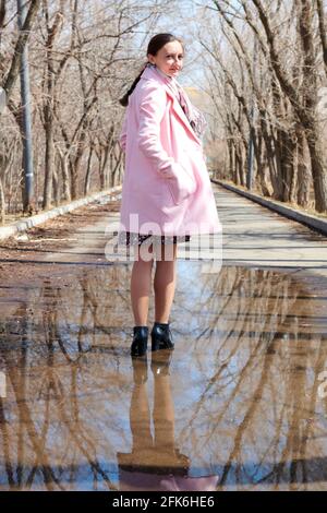 woman walking in a puddle with trees reflection Stock Photo