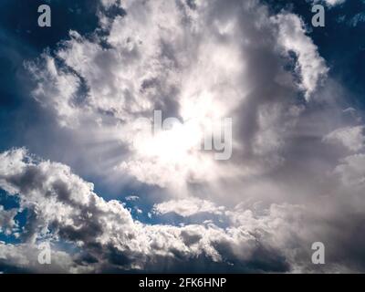 Sun rays shining through the clouds on the blue sky. Sunlight. Blue sky. Cloudy landscape. Overcast. Atmospheric phenomenon. Weather forecast. Backgro Stock Photo