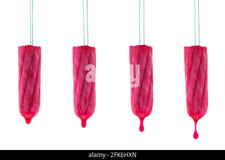 4 New unused tampon hanging with dripping red syrup liquid drop that looks like blood, isolated on white background Stock Photo
