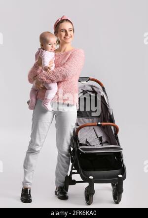 Woman with her cute baby and stroller on white background Stock Photo