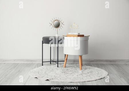 Modern bedside table with pouf near white wall in room Stock Photo
