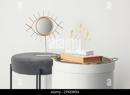 Modern bedside table with pouf near white wall Stock Photo