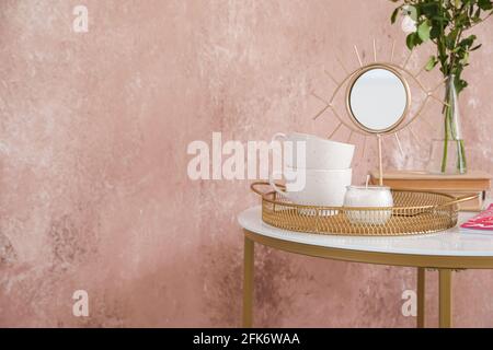 Cups with candle and mirror on table near color wall Stock Photo
