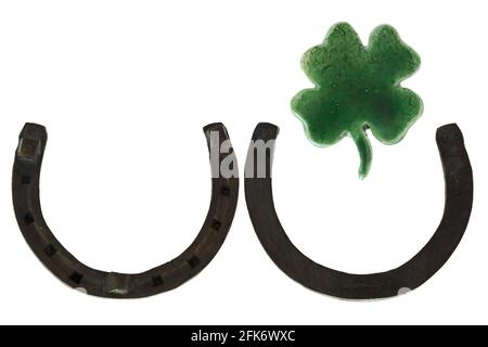 Steel metal horseshoes pointing upwards, green Ceramic Shamrock Four leaf lucky clover as a sign of good luck isolated on white background Stock Photo