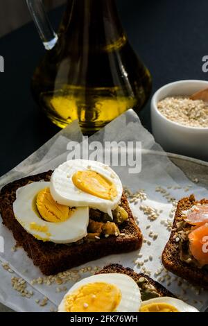Toasted breads with poached eggs, avocado and salmon. Guacamole sandwiches. Healthy breakfast. Olive oil. Sesame seeds. Vegetarian healthy eating. Die Stock Photo