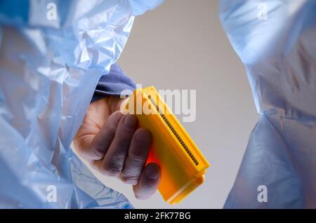 The hand throws the yellow video game cartridge into the trash. A man holds TV game cartridge over an trash can. Bottom view. Indoors Stock Photo