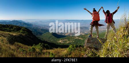 Panorama , two female hikers climbing up mountain cliff Stock Photo