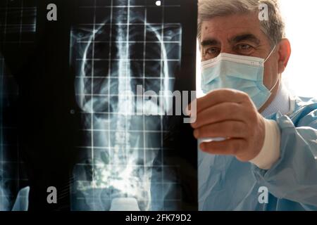 Senior male doctor with protective mask examining a woman patient in hospital, checking X-ray. Stock Photo