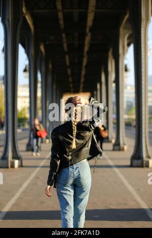 Back view woman wearing black leather jacket walking in Milan. Stock Photo