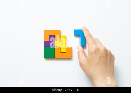Set of color blocks puzzle pieces and hand holding last one piece on white background. Creative thinking, idea, problem solving, success concept. top Stock Photo