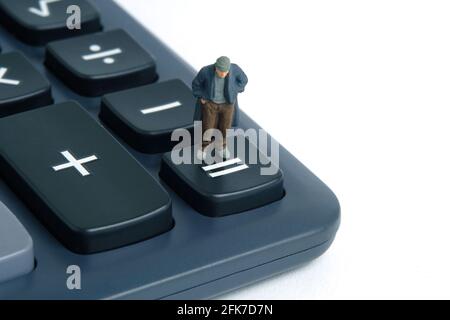 Poor man with no money left standing above calculator. Miniature tiny people toys photography. isolated on white background. Stock Photo