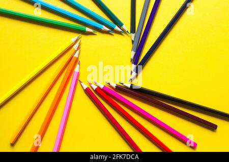 Set of colorful pencils on a yellow background is laid out in a circle in the shape of the square. Copyspace, frame. Back to school, artist, drawing l Stock Photo