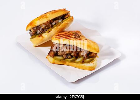 Street food sandwiches with meat, pickled cucumbers on a white plate. White background. Delicious sandwiches. Side view. Stock Photo