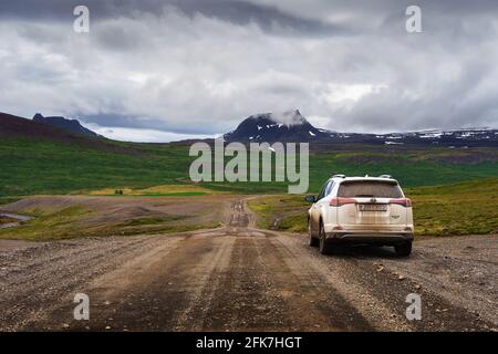 White rental SUV vehicle on the dirt road of Westfjords region in Iceland Stock Photo