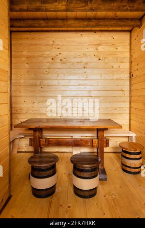 Wooden table with small wooden stools in the shape of wine barrels around in the room. Stock Photo