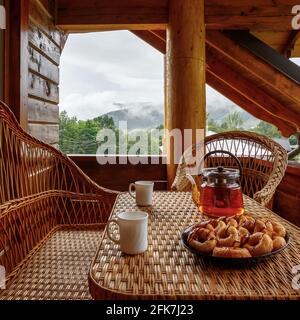 Breakfast on the balcony of a wooden house with wicker furniture. Stock Photo