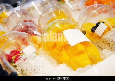 Pieces of pineapple and other fruits with chia seed yoghurt are laid out in plastic disposable cups and sold in store. Healthy vegetarian foods concep Stock Photo