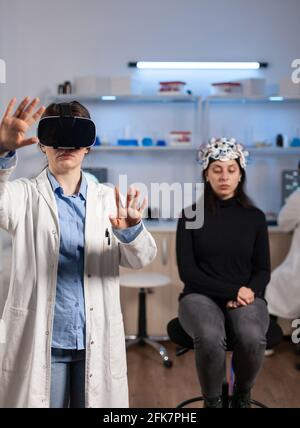 Laboratory doctor experiencing virtual reality using vr goggles in medical neurological research lab. Physician therapist using medical innovation equipment device glasses, analysing brain scan. Stock Photo