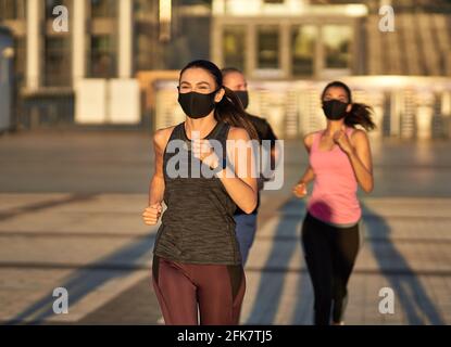 Sportive lady running on the street together with other athletes Stock Photo