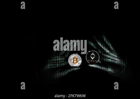 Hands in a black gloves holding bitcoin and Ethereum coin. International hacker is trying to steel your crypto currencys. Blockchain security. Thief with laptop is hacking governments computers. Phishing attacks.  Stock Photo