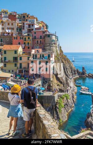 Manarola, La Spezia, Liguria, Italy.  Couple looking out over Manarola, one of the five villages of the Cinque Terre, or Five Lands. The Cinque Terre Stock Photo