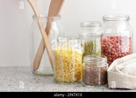 Variety of cereals, grains, pasta, seeds in glass jars uncooked on white kitchen background, closeup, zero waste, eco friendly, balanced diet food, he Stock Photo