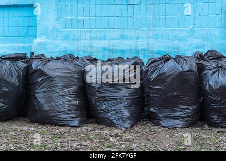 https://l450v.alamy.com/450v/2fk7ygf/row-of-black-plastic-garbage-bags-on-a-blue-background-of-the-house-bags-of-garbage-seasonal-cleaning-of-city-streets-cleaning-service-2fk7ygf.jpg
