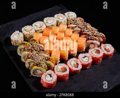 Large square stone board with sushi set of different types of rolls. Japanese traditional cuisine. Sashimi and nigiri sushi. Stock Photo