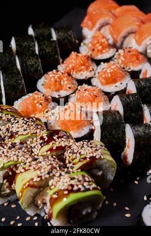 Close up set of sushi with salmon, cucumber, cream cheese, avocado and sesame seeds. Japanese traditional cuisine.