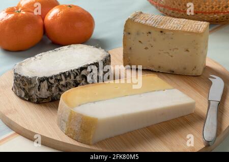 Cheese platter with different types of cheese, Double Dutch cheese, Monte Enebro from Spain and Taleggio tartufo from Italy close up as a snack or app Stock Photo