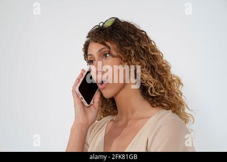 UK. 2021.  Attractive mixed race woman using a smartphone, to make a telephone call. Stock Photo