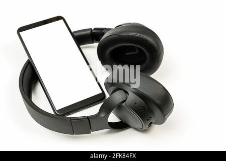 black wireless headphones and smartphone on white background, blank screen mockup, copy space Stock Photo