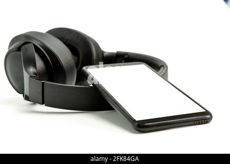 black wireless headphones and smartphone on white background, blank screen mockup, copy space Stock Photo