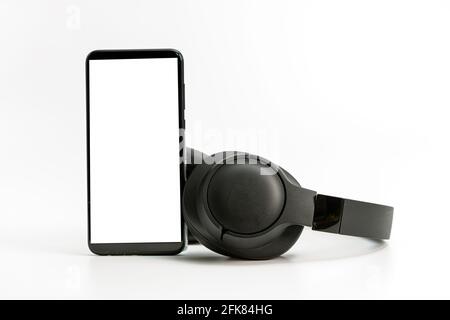 black wireless headphones and smartphone on white background, blank screen mockup, copy space Stock Photo