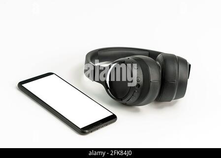 black wireless headphones and smartphone on white background, blank screen mockup, copy space Stock Photo