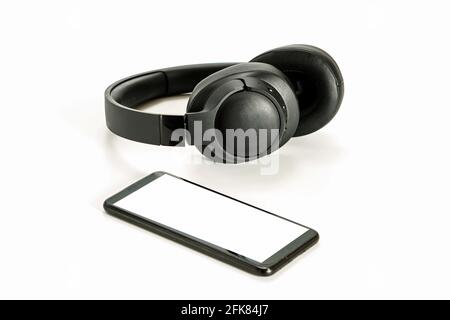 black wireless headphones and smartphone on white background, blank screen mockup, copy space Stock Photo