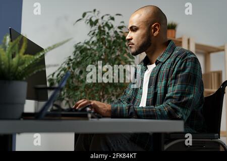 Disabled african american man sitting at the table and working on computer Stock Photo