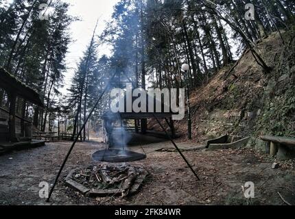 South Poland: Barbecue location in the middle of the forest surrounded with tall trees. Wilderness wide angle view of smoke coming from fire against a Stock Photo