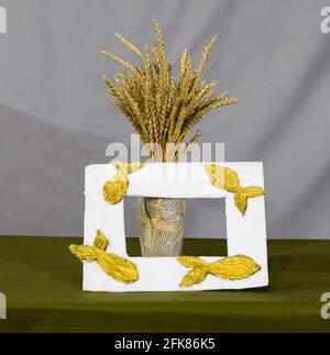 Cardboard vase from newspapers, in a vase of wheat. A photo frame with fish. Stock Photo