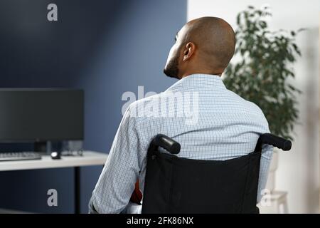 Disabled african american man sitting at the table and working on computer Stock Photo
